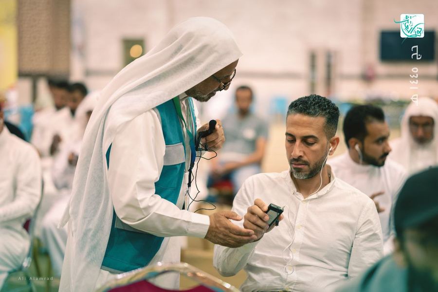 مرشد يسلّم جهاز استقبال لأحد الحجاج